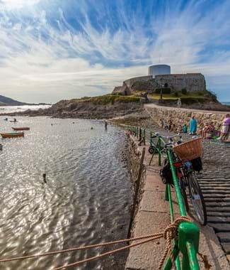 The walkway up to Castle Cornet with the sea and fishing boats on your right