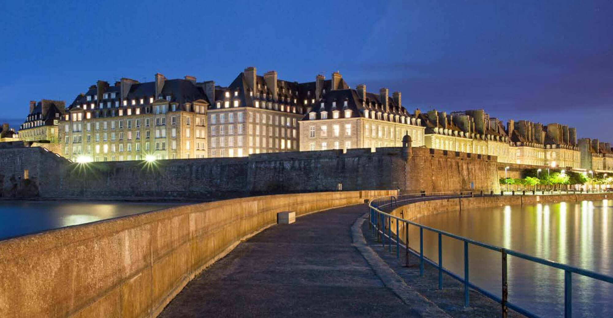 beautiful walls of st malo lit up at night with blue black sky in background